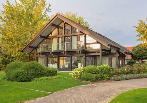 Moderne Architektur eines Hauses mit Garten Elegantes Haus mit Balkon, umgeben von grünem Garten und Bäumen