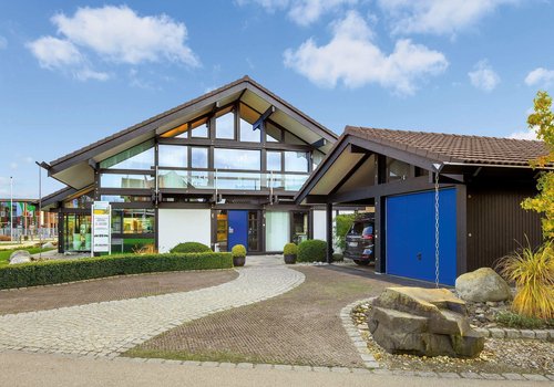 HUF Musterhaus Muenchen 1 Architektonisches Design eines Hauses mit grünem Garten und Garageneinfahrt