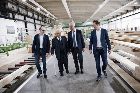 Besuch in einer Holzverarbeitungshalle Vier Männer gehen durch eine Holzverarbeitungshalle