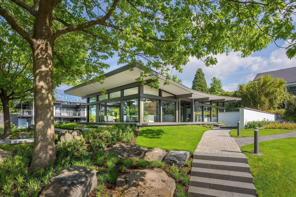 Moderne Architektur in einer grünen Umgebung Ein zeitgenössisches Gebäude umgeben von Bäumen und Gartenlandschaft