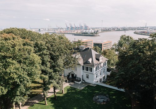 Historisches Gebäude mit Blick auf den Hafen Elegantes Haus umgeben von Bäumen mit Hafenansicht im Hintergrund